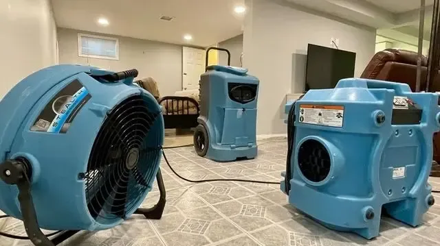 Air movers and a dehumidifier drying a room after water damage
