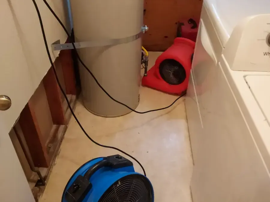 Air movers sit on a laundry floor beside a washer and water heater