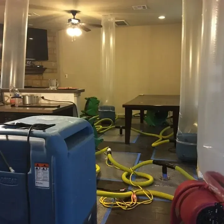 Drying hoses and equipment extend across a room during interior water mitigation