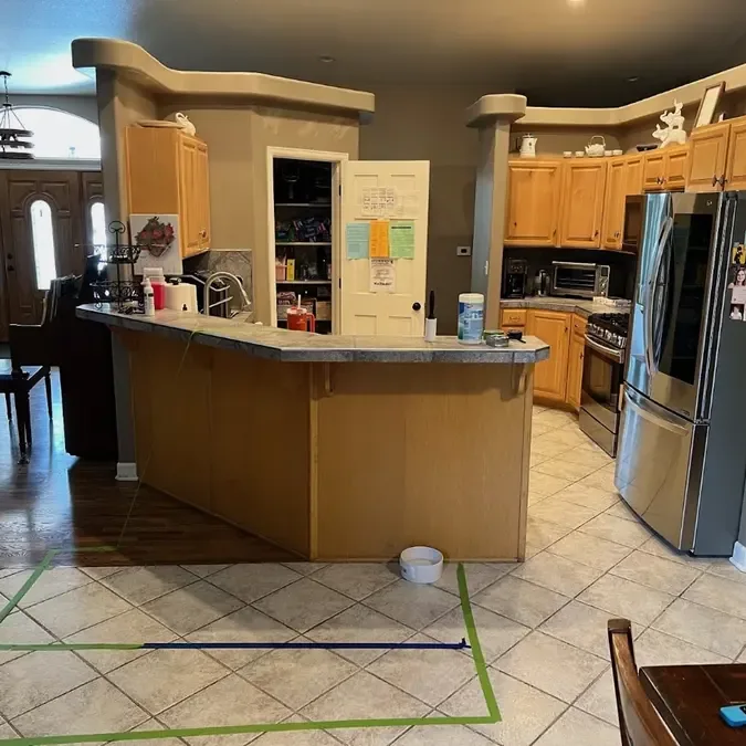 Tape strips mark measurement areas across the tile floor inside a kitchen