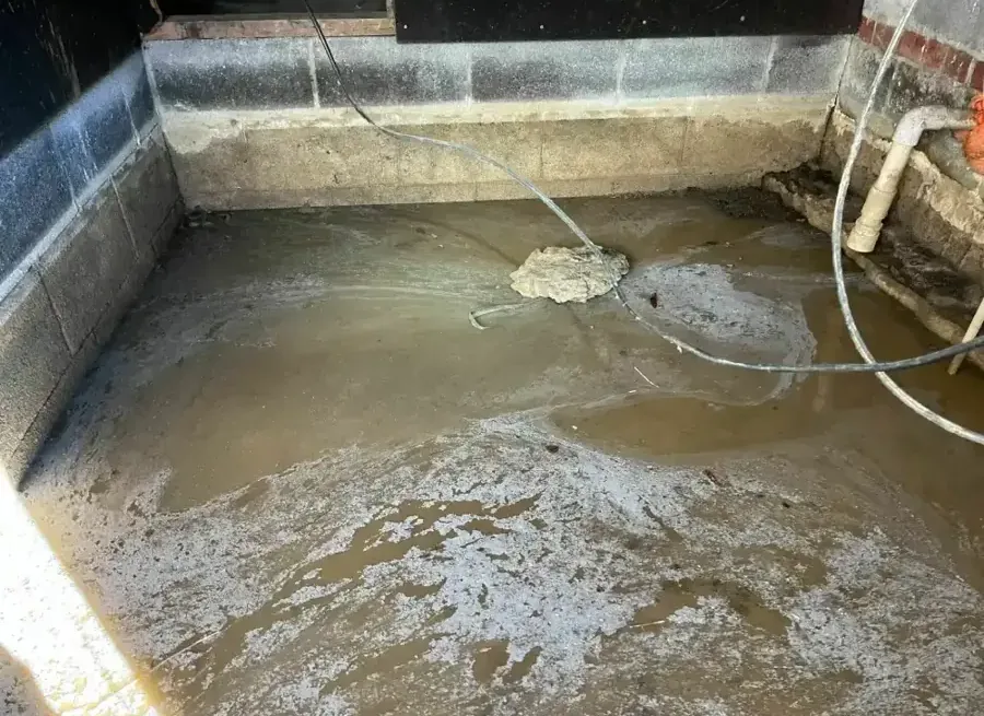 Standing water across a confined underfloor area bordered by concrete block walls